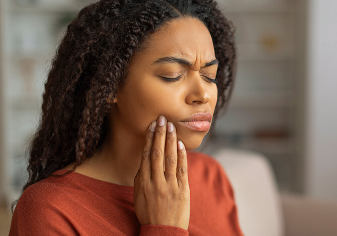 woman holding her jaw in pain